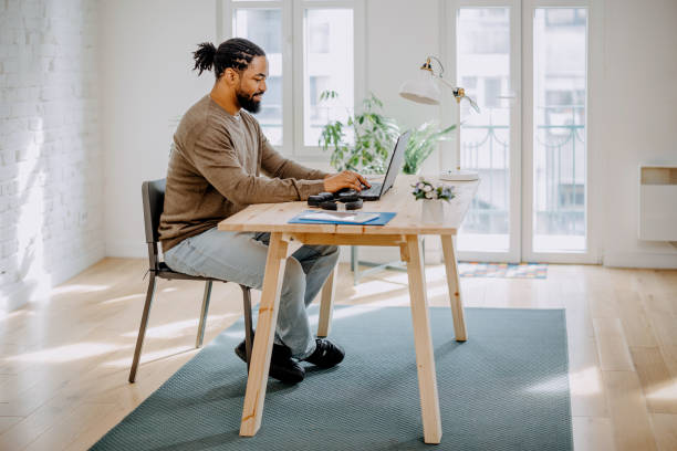 istock Young black man using laptop at home, typing on keyboard, writing email or message, chatting, shopping, successful freelancer working online on computer 1388373298