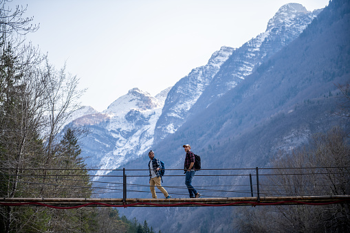 Hikers crossing the suspension bridge over Soca river in Julian Alps, Slovenia, Europe.