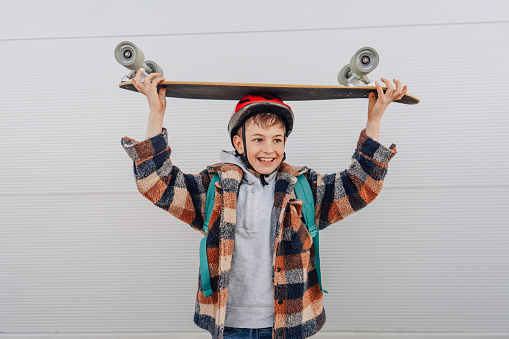 Photo of a schoolboy holding his skateboard