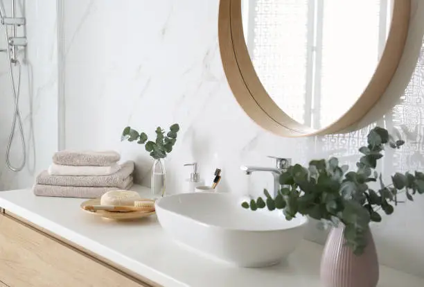 Photo of Fresh eucalyptus branches and bathroom items on countertop