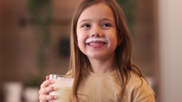Happy girl drinking fresh yogurt at home.