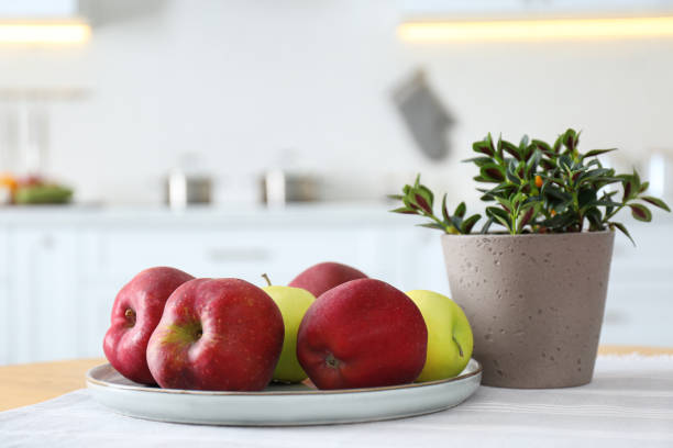 istock Fresh ripe apples and plant on table in kitchen 1388376943