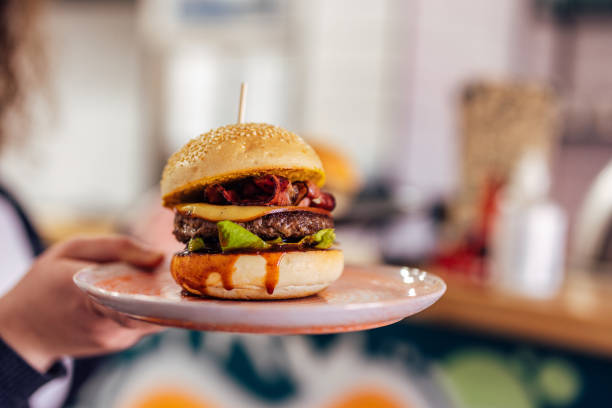 istock Someone holding a plate with a burger, looking delicious. 1388380061