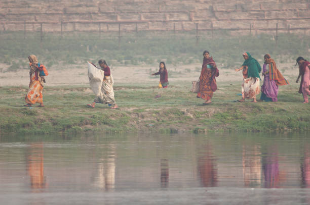 Indian women walking along a riverside in the Yamuna River. stock photo