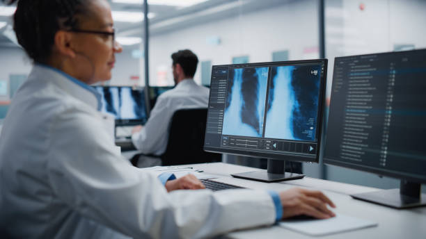 laboratorio ospedaliero moderno: il medico donna nera sta lavorando al computer analizzando il torace, i raggi x delle ossa sullo schermo. medico afroamericano professionista che fa ricerca di trattamento ad alta tecnologia - radiologist foto e immagini stock