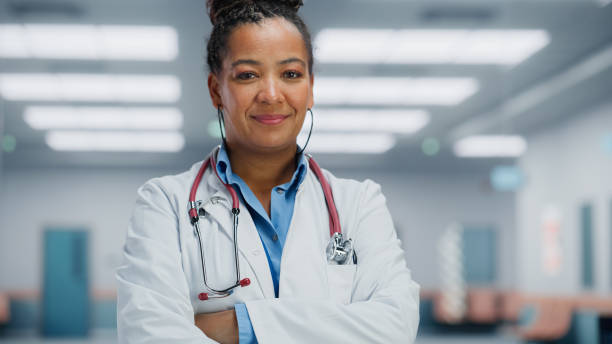 medical hospital medium portrait: afroamerikanische ärztin nimmt brille und schaut aufrichtig in die kamera und lächelt. erfolgreicher arzt im weißen laborkittel bereit, leben zu retten - lab coat women one person female stock-fotos und bilder