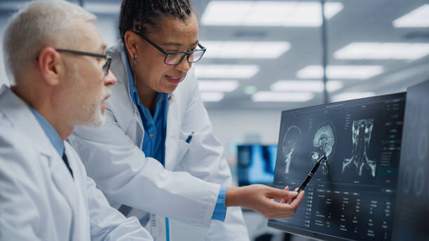 hôpital médical: neurologue et neurochirurgien parlent, utilisent l’ordinateur, analysent l’irm du patient, diagnostiquent le cerveau. laboratoire de la clinique de santé: deux médecins professionnels examinent la tomodensitométrie fonctoning trou - image par résonance magnétique photos et images de collection