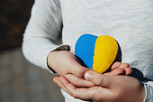 Small little kid hold heart shaped stone with Ukraine national flag or anthem