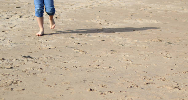 istock Child walking along the beach 1388391107