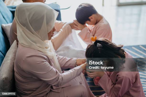 Malay Muslim Children In Traditional Clothings Asking Forgiveness To Their Parents During Hari Raya Aidilfitri Celebration Stock Photo - Download Image Now