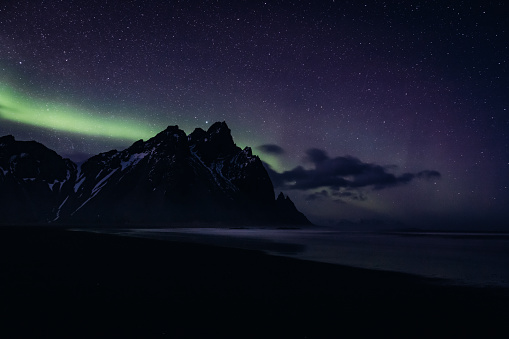 Vestrahorn Mountain Range Aurora Polaris - Polar Lights - Northern Lights at Night Stokksnes, Southeast Iceland. Volcanic Black Beach at Vestrahorn Mountain with arctic polar lights - northern lights aurora in wintertime. Black Beach, Sea and famous Vestrahorn Mountain Range. Aurora Night Skyscape. Vestrahorn Mountain, Stokksnes, South East Iceland, Nordic Countries, Northern Europe.