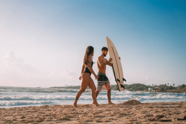 Surfers walking on the beach holding a surfboard