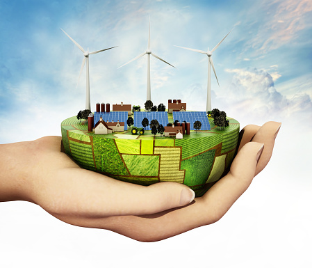 Hand holding hemisphere covered with green fields, clean energy equipments and farms. Sustainability and agriculture concept.