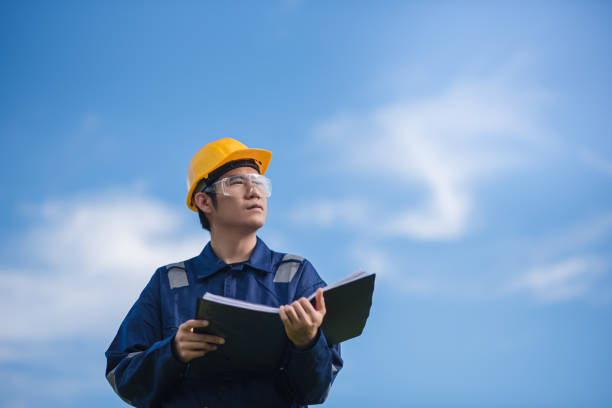 An Engineer is holding a document and looking away. stock photo