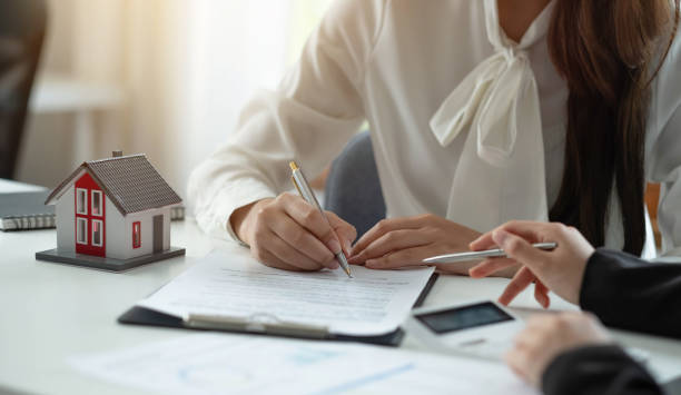 istock Close up woman signs contract behind home architectural model 1388396837