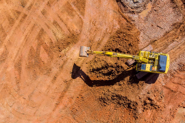 istock Digger on earthworks in excavator dig the trenche at construction site on arial view 1388397681