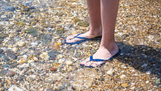 istock Mens feet in sandals on the beach. 1388398506