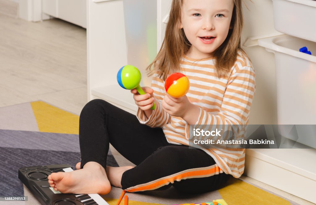 Child playing maracas at home. Child portrait looking to the side Child playing maracas at home. Leisure and education at home Child Stock Photo