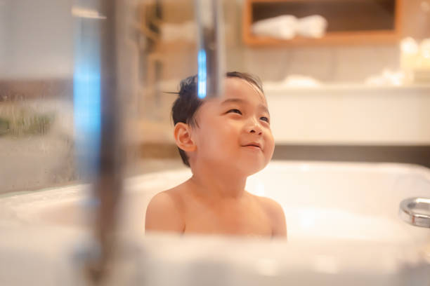 Asian boy happily taking a bath in the tub