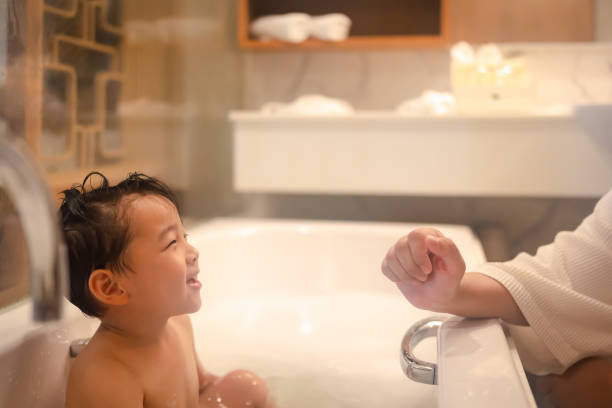 Asian boy happily playing with mom and taking a bath in the tub. stock photo