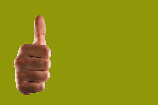 Human hand thumbs up on the green background with clipping path and copy space