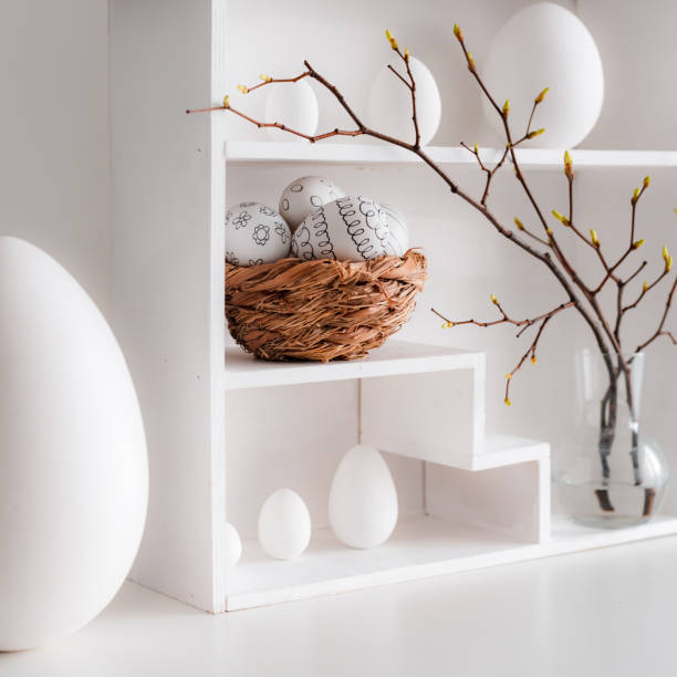 istock Home minimalist interior with Easter decor. Branches with budding buds in a glass vase on shelves in the shape of a house, 1388402483