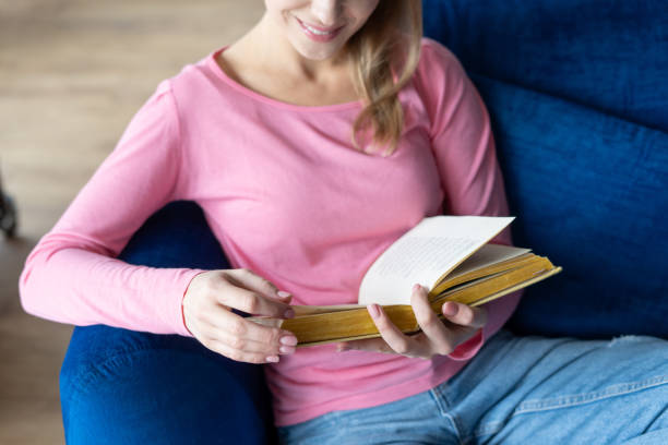 istock Happy woman relax on couch, reading paper book 1388404658