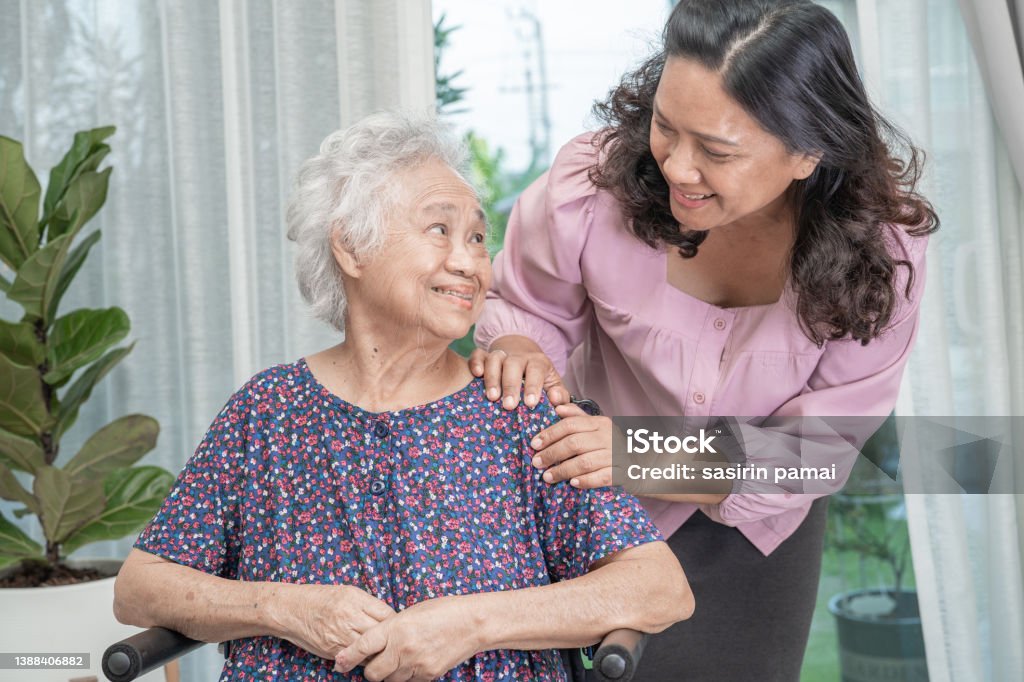 Help Asian senior or elderly old lady woman sitting on wheelchair and wearing a face mask for protect safety infection Covid 19 Coronavirus. Mobility Walker Stock Photo