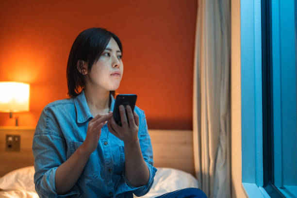 istock Woman sitting on bed and using smart phone at night 1388408103