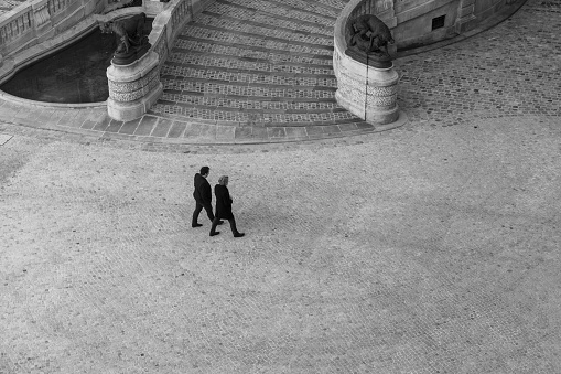 Two business people walking near a stone staircase in Paris, France.