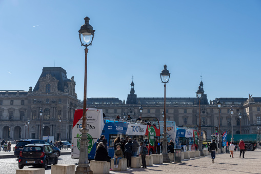 Street photography of a locals and tour buses near the Louvre museum., Paris, France