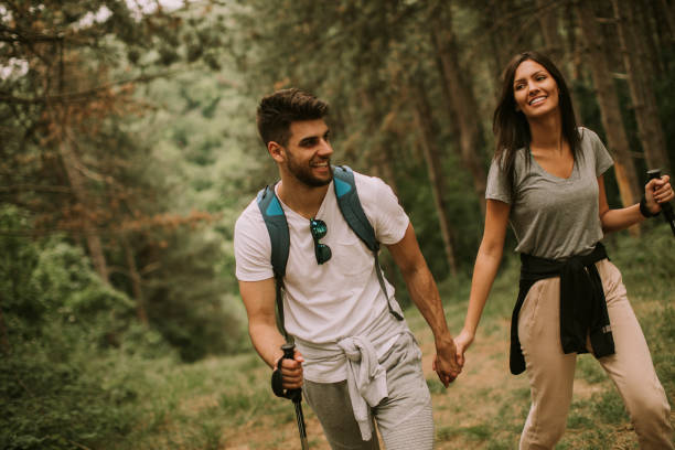 istock Couple of hikers with backpacks walk through the forest 1388410706