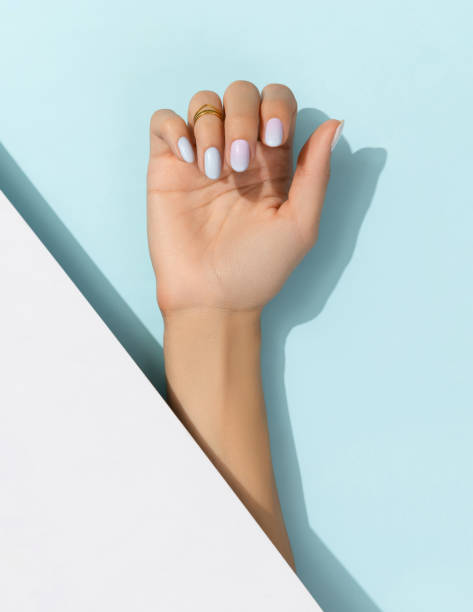 istock Womans hands with trendy manicure on blue background. Summer nail design 1388414433