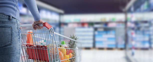 Woman pushing a shopping cart at the supermarket stock photo
