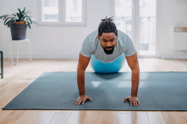 istock Handsome black man doing exercise and stretching , practicing flexibility with pilates ball at the home. 1388419255