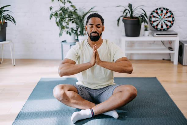 istock Young black man meditating in his appartment. Breathing technique. 1388419304