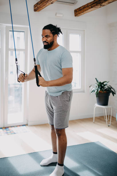 istock Home workout routine. Black man doing suspension straps exercises 1388419327