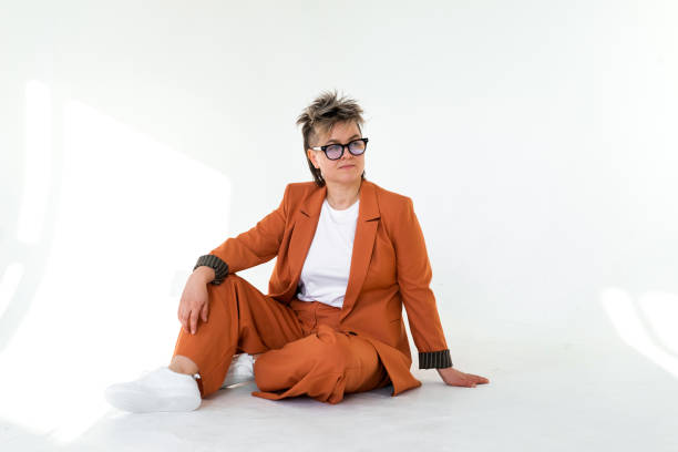 istock young emotional non binary person wearing orange color suit posing at studio 1388425745