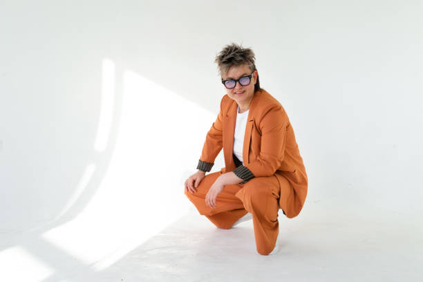 istock young emotional non binary person wearing orange color suit posing at studio 1388426969