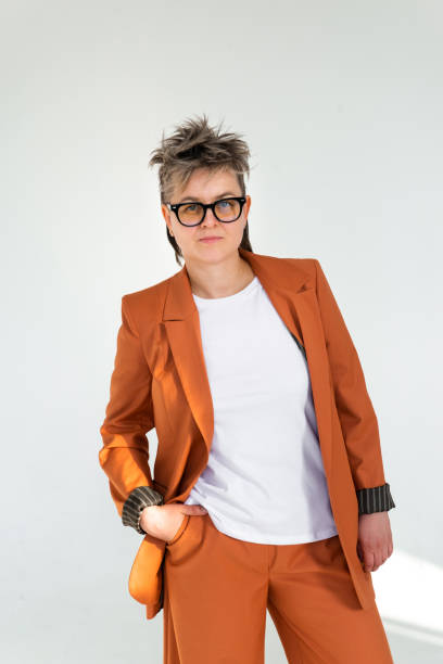 istock young emotional non binary person wearing orange color suit posing at studio 1388427419
