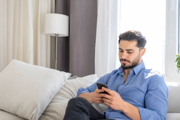 istock Handsome young man texting by phone 1388427497