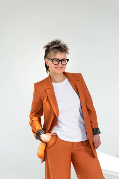 istock young emotional non binary person wearing orange color suit posing at studio 1388427546