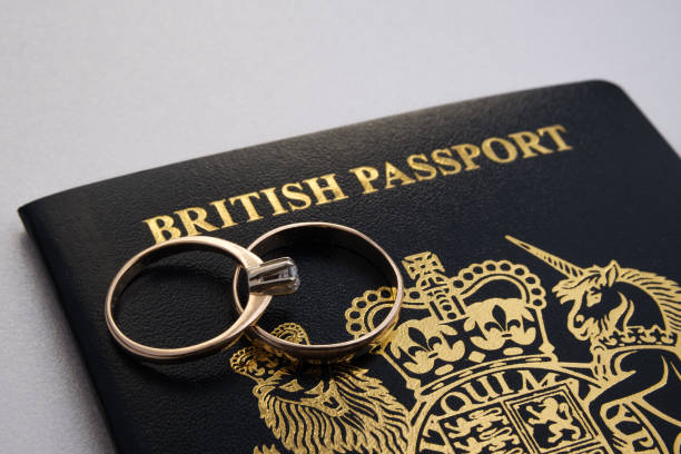 Gold rings on top of a new dark blue British passport. stock photo