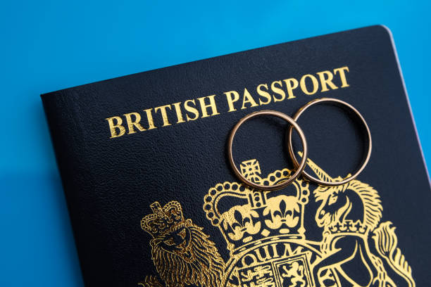 Gold rings on top of a new dark blue British passport. Concept for UK Fiance visa or Spouse Visa. stock photo
