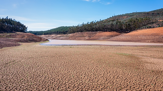 Landscape of low water and dry land in advance, severe drought in the reservoir of Portugal. Ecological disaster, soil dehydration. High quality photo