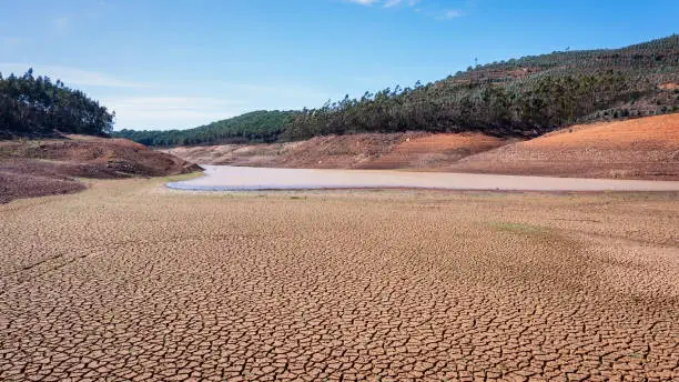 Landscape of low water and dry land in advance, severe drought in the reservoir of Portugal. Ecological disaster, soil dehydration. High quality photo