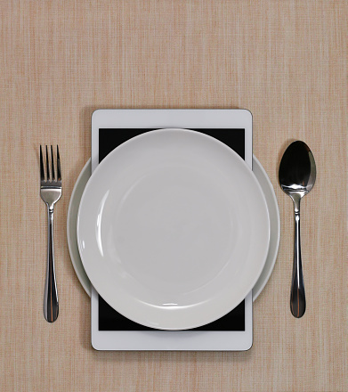 Tableware set integrated with a tablet on the tablecloth. Ordering food.
