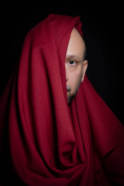 istock Man covered with red cloth against a black background. 1388430318