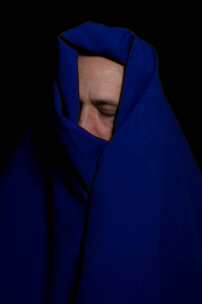 istock Man covered with blue cloth against a black background. 1388430342