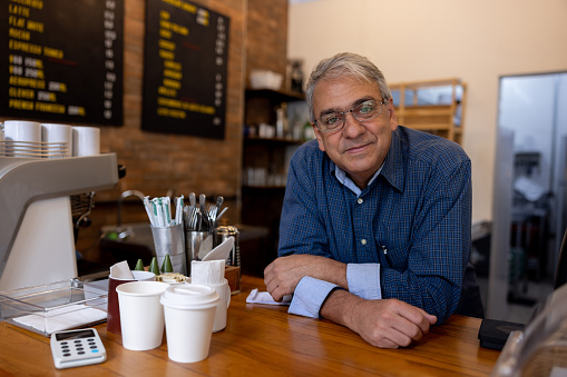 Brazilian business owner at a cafe leaning on the bar counter while looking at the camera